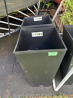 Large and smaller black plastic planters viewed from the side showing label and number sticker