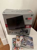 Sony PS3 box with 320GB label and five game cases front view