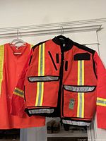 Safety jacket and safety shirt hanging on hangers with full front visible
