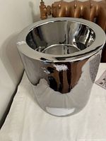 Close-up side view of tall cylindrical silver dog dish with polished reflective surface, showing height and recessed bowl interior.