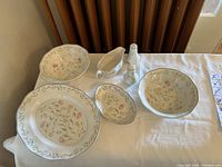 Vintage Johnson Brothers china set on table including plates, bowls, gravy boat, small dish, and salt and pepper shakers all with matching floral pattern.