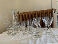 Photo showing the full collection of clear crystal glassware items, including glasses and decanter on a white cloth with radiator background.