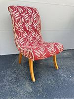 Side angle view showing curved seat and back with fringed tapestry upholstery and wooden legs.
