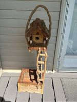 Birdhouse planter showing frontal view with visible ladder and moss roof under natural light
