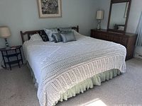 King size bed fully covered with the white crocheted coverlet, showing its size and texture.