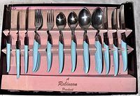 Full set of flatware in original pink display tray, showing six each of knives, forks, spoons, and cutting knives with turquoise Bakelite handles.