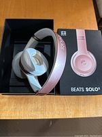 Beats Solo3 wireless headphones in rose gold inside original box on wooden surface.