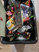 Overhead shot of large plastic bin filled with assorted LEGO bricks, baseplates, and partial sets