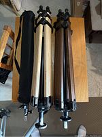 Four camera tripods with two wooden Berlebach models and black carrying bag