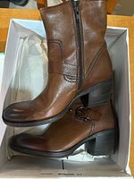 Side view of the tan leather Clarks women's boots inside the box showing shape, zipper and buckle detail.