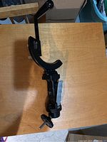 Full view of the black custom camera bracket showing the handle and mount components on a wooden surface.