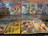 21 Walt Disney comic books laid out on a table in plastic protective sleeves showing colorful covers with Donald Duck, Mickey Mouse, Uncle Scrooge and others.