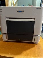 Front view of DNP DS-RX1HS printer showing DNP logo, front paper tray and indicator light panel.