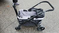 Side view of black and gray stroller wagon showing canopy, frame, and wheels.