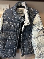 Front and partial inside view of Levi's puffer jacket showing blue and white bandanna patchwork print and Levi's label inside collar.