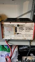 Front view of Motomaster 6 Amp Battery Charger with visible brand logo, specifications, and battery clip cables.