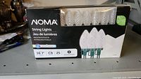 Box of NOMA string lights with 25 C9 LED bulbs on a workshop table