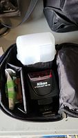 Nikon SB-700 flash head inside bag pocket with white diffuser cap on top