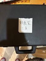 Black plastic carrying case closed with a note on top in Chinese characters.