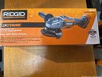 Photo showing front side of the retail box with branding Ridgid Octane, specifying brushless 18V 4-1/2 inch angle grinder with over 40% more power and image of the grinder.