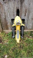 Front view of Ski-Doo kids snow scooter toboggan showing yellow body, black skis, and handlebar covers.