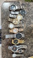 Full assortment of metal band men's watches laid out on table