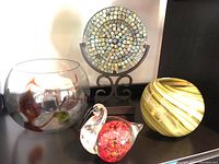 View of all four art glass pieces grouped together: mosaic plate, large bowl, swirled vase, and glass swan figurine.
