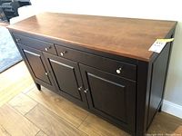 Front view showing three drawers above and three paneled doors below, with silver round knob handles and medium brown wooden top.