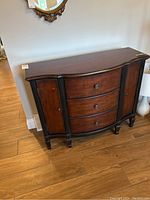 Full view of wood cabinet showing curved front, three drawers, and side cabinets