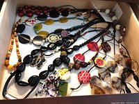 Photo showing a drawer full of assorted costume jewelry beaded necklaces in various colors and materials including wood, plastic, and resin beads.