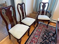Group view of four side chairs and two armchairs arranged around dining table.