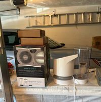 One humidifier disassembled showing base unit and water tank with packaging and extra filters stacked on top.