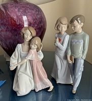 Front and side views of the Lladro figurine showing a woman in a white dress hugging a young girl in a pink dress.