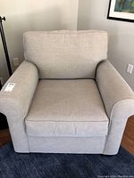 Front view of beige upholstered armchair showing rolled arms and removable cushions.