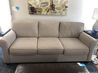 Front view of beige upholstered sofa in room setting