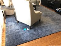 Full room view showing the rug laid under living room chairs and table