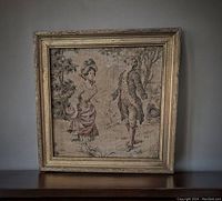 Front view of framed antique French tapestry showing full piece with man and woman in period dress, vintage gold frame visible.