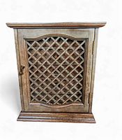Front view of vintage wooden jewelry box with lattice wooden door and brass knob.