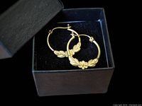 Pair of vintage 14k gold flower wreath hoop earrings placed in a black box.