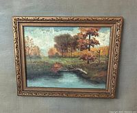 Frontal photo of original oil on board fall landscape painting with decorative gold frame.