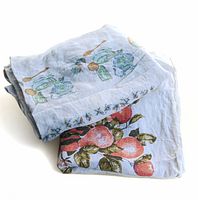 Two folded vintage linen/cotton tablecloths with blue kitchen items and apple print designs.