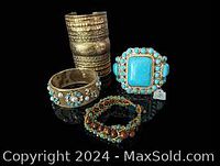 Four vintage gold tone bracelets shown together on black reflective surface, including bangles with turquoise stones and a beaded bracelet