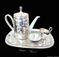 Side angle showing assembled teapot with metal thermal hood, creamer, sugar bowl and tray with hammered texture