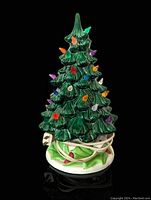 Front view of the ceramic Christmas tree with colorful bulbs and attached electric cord wrapped around base.