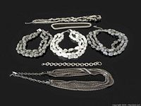 Full view of the vintage jewelry lot including three crystal bead necklaces and four silvertone chain bracelets and necklaces.