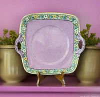 Front view of square ceramic platter plate with floral border and purple center.