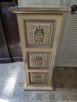 Front view of the nightstand cabinet showing three painted floral panels on the door, in Pennsylvania Dutch folk art style.