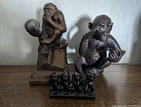 Photo of three monkey-themed statuettes on a wooden surface