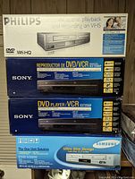 Stack of Philips, Sony (SLV-D380P), Samsung DVD/VCR combo boxes