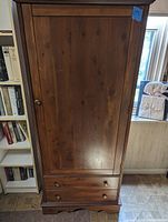 Full front view of Lane cedar wood armoire showing single door and two lower drawers with wooden knobs.